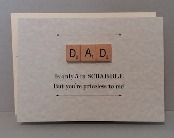 May include: A card with a light gray background and the word "DAD" spelled out with Scrabble tiles. The text below reads "Is only 5 in SCRABBLE But you're priceless to me!"