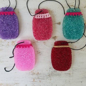 May include: Five hanging mason jar-shaped car air fresheners in various colors, including purple, pink, red, teal, and white. Each jar has a decorative trim around the top.