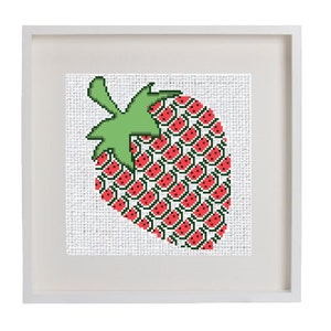May include: A framed cross-stitch artwork depicting a red strawberry with green leaves. The strawberry is made up of smaller red strawberries with black seeds.