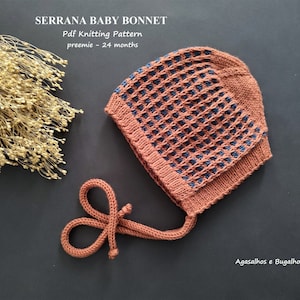 May include: A brown and blue knitted baby bonnet with a tie. The bonnet is on a dark gray surface. The text "Serrana Baby Bonnet" and "Pdf Knitting Pattern" is above the bonnet. The text "preemie - 24 months" is below the bonnet. The text "Agasalhos e Bugalhos" is in the bottom right corner of the image.