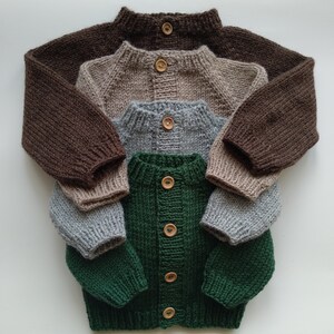 Puede incluir: Una pila de cuatro c&aacute;rdigans de punto de manga larga en colores marr&oacute;n oscuro, beige, gris claro y verde oscuro. Cada c&aacute;rdigan presenta cuello, pu&ntilde;os y dobladillo acanalados, con un bot&oacute;n de madera en el cuello para los tres superiores.