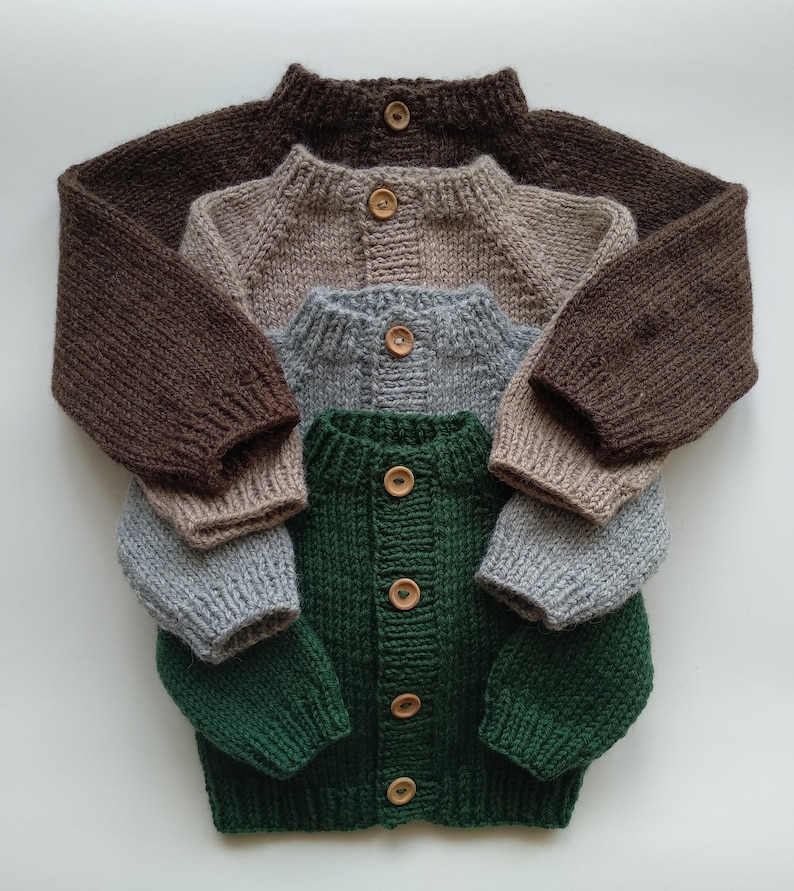 Puede incluir: Una pila de cuatro c&aacute;rdigans de punto de manga larga en colores marr&oacute;n oscuro, beige, gris claro y verde oscuro. Cada c&aacute;rdigan presenta cuello, pu&ntilde;os y dobladillo acanalados, con un bot&oacute;n de madera en el cuello para los tres superiores.