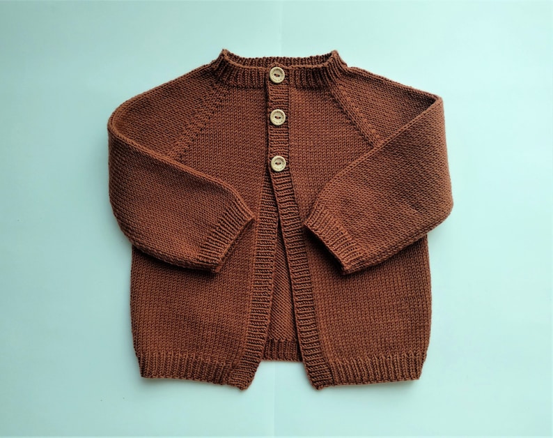 May include: A brown knitted cardigan with a button closure. The cardigan has a round neckline and long sleeves.