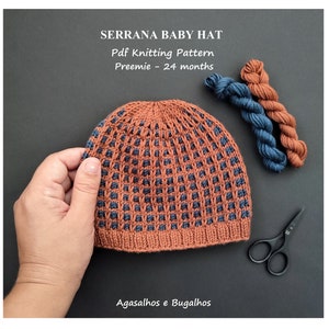 May include: A knitted baby hat in brown and navy blue, with a textured pattern. The hat is held by a hand, with two skeins of yarn and small scissors nearby. Text on the image reads "SERRANA BABY HAT" and "Pdf Knitting Pattern".