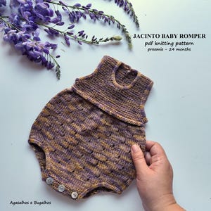 Puede incluir: Un pelele de punto para bebé en hilo jaspeado morado, dorado y marrón con patrón texturizado, cuello redondo y tres botones pequeños en la parte inferior. Texto: JACINTO BABY ROMPER pdf knitting pattern preemie - 24 months.