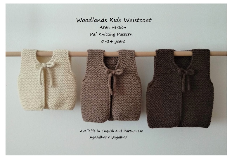 May include: Three knitted waistcoats for children in beige, brown, and dark brown. The waistcoats have a tie at the neck and are available in sizes 0-14 years. The text "Woodlands Kids Waistcoat" is at the top of the image. The text "Aran Version" is below the title. The text "Pdf Knitting Pattern" is below the version. The text "0-14 years" is below the pattern. The text "Available in English and Portuguese" is at the bottom of the image. The text "Agasalhos e Bugalhos" is below the availability text.