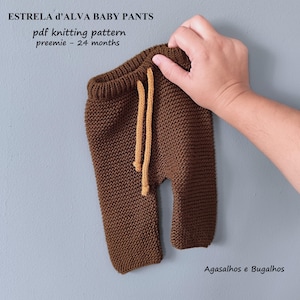 Peut inclure: Un pantalon de bébé en tricot marron avec un cordon de serrage. Le pantalon est tenu par une main. Le texte "ESTRELA d'ALVA BABY PANTS" est en haut, avec "pdf knitting pattern preemie - 24 months" en dessous.