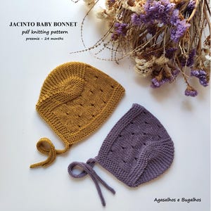 Peut inclure: Deux bonnets pour bébé tricotés en jaune moutarde et violet poussiéreux, avec un motif à œillets texturé et des liens. Le texte indique : JACINTO BABY BONNET pdf knitting pattern preemie - 24 months. Fleurs séchées visibles.