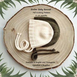 May include: Two knitted baby bonnets, one cream and one olive green, with ties. The bonnets are on a wooden surface. Ember Baby Bonnet Pdf Knitting Pattern 0-24 months. Available in English and Portuguese. Agasalhos e Bugalhos.