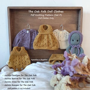 May include: A collection of knitted doll clothes including a purple cardigan, a mustard yellow dress, a cream cardigan, a mustard yellow romper, and a mustard yellow bonnet. A blue knitted doll is present. Text reads The Oak Folk Doll Clothes.