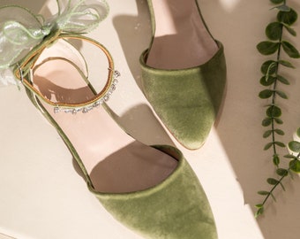 May include: A pair of green velvet pointed toe flats with a delicate bow and rhinestone embellishment on the ankle strap.