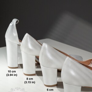May include: Four pairs of white heeled shoes with different heel heights. The heels measure 3.94 inches, 3.15 inches, 2.36 inches, and 1.96 inches.