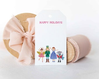 Könnte beinhalten: Ein weißer Geschenkanhänger mit dem Text "HAPPY HOLIDAYS" in rosa gedruckt. Der Anhänger zeigt eine bunte Illustration einer Ballerina, eines Nussknackers, einer Prinzessin und einer Maus.