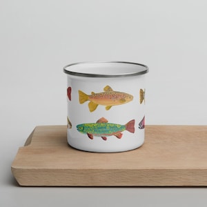 May include: A white enamel mug featuring a repeating pattern of various freshwater fish illustrations. The fish are depicted in vibrant colors including yellow, green, and orange with detailed scales and fins. The mug has a silver-toned metal rim.