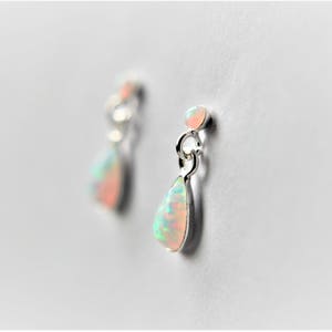 May include: A pair of silver teardrop earrings with iridescent opal stones.