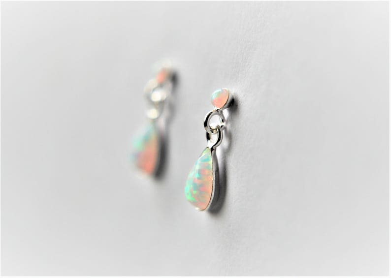 May include: A pair of silver teardrop earrings with iridescent opal stones.