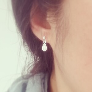 May include: Silver teardrop earrings with a small bead at the top.