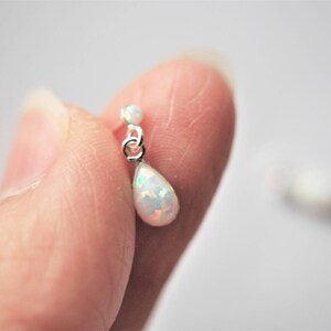 May include: A pair of silver teardrop earrings with a white opal stone.