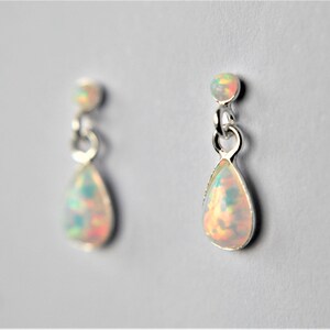 May include: A pair of silver teardrop earrings with iridescent opal stones.