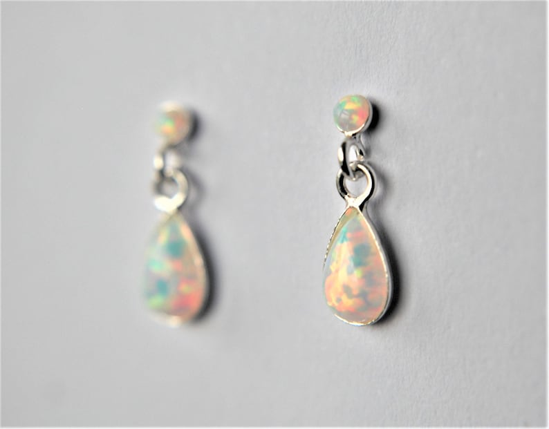 May include: A pair of silver teardrop earrings with iridescent opal stones.
