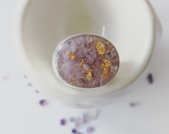 May include: A silver ring with a purple and gold resin inlay. The resin is filled with small pieces of purple and gold.
