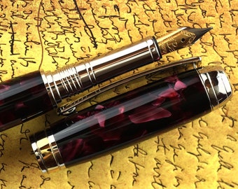 Könnte beinhalten: Ein schwarzer und burgunderfarbener Füllfederhalter mit goldenen Akzenten und einer feinen Feder. Der Stift besteht aus einem marmorierten Harzmaterial und hat ein klassisches Design.