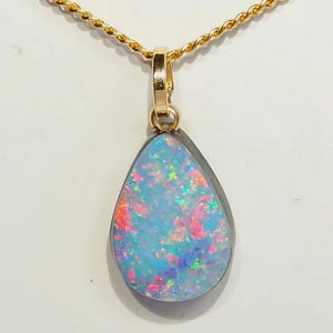 May include: A teardrop opal pendant with a gold chain. The opal displays a mix of blue, pink, and green colours. The pendant is set in a silver bezel. The gold chain has a twisted rope design.