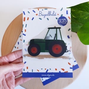 Może przedstawiać: Karta z zielono-czarnym traktorem z czerwonymi kołami. Karta zawiera tekst "Bügelbild" i "STYPS studio for gestaltung" z obramowaniem z konfetti. Widoczna jest również strona internetowa www.styps.de.