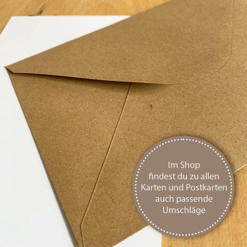 May include: A brown paper envelope with a white circle sticker that says "Im Shop findest du zu allen Karten und Postkarten auch passende Umschl&auml;ge".