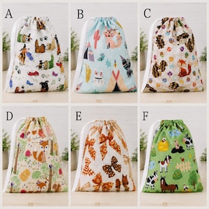 May include: Six drawstring bags labeled A through F. Bag A features dogs, B has foxes and teepees, C shows woodland animals, D displays foxes in a forest, E features brown bows, and F depicts farm animals on a green background with white cords.