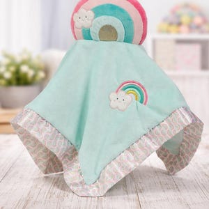 May include: A soft, mint green baby blanket with a rainbow and cloud design. The blanket has a satin trim with a pink and white pattern. A rainbow and cloud applique is on the blanket.