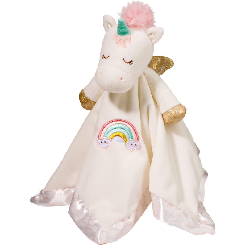 May include: A white plush unicorn toy with a pink pom-pom mane, gold accents, and a rainbow embroidered on a cream-colored blanket. The blanket has a satin trim with a pink dotted pattern.