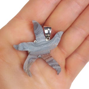 May include: A silver pendant featuring a grey and brown agate starfish with a silver bail.