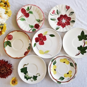 May include: Set of six vintage floral patterned teacups and saucers. The saucers feature a variety of floral designs, including red flowers, yellow flowers, and green leaves.