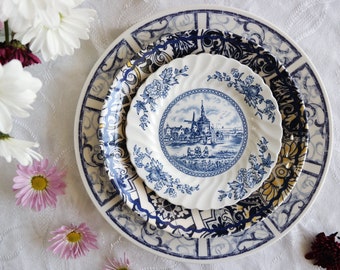 Puede incluir: Tres platos de cerámica azul y blanco con una escena de molino de viento holandés en el plato más pequeño. Los platos están apilados uno encima del otro.