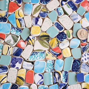 May include: A collection of colorful, patterned ceramic tiles in various shapes and sizes. The tiles are arranged in a random pattern and feature a mix of blue, green, yellow, red, and white colors.