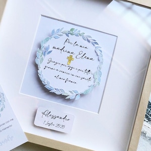 Puede incluir: Una tarjeta blanca enmarcada con una corona acuarela azul y verde con una cruz dorada y el texto "Per la mia madrina Elena" y "Grazie per oggi e per tutti i giorni a venire in cui sarete al mio fianco." La tarjeta tambi&eacute;n incluye el texto "Alessandro 1 Luglio 2020".