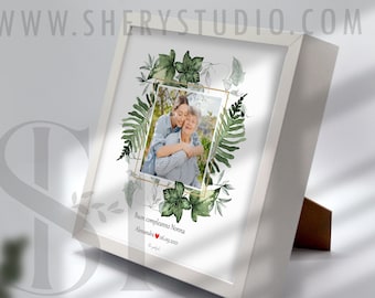 Puede incluir: Foto enmarcada en blanco con un diseño floral verde y una foto de dos personas abrazándose. El texto "Buon compleanno Nonna" y "Alessandro, Maggio 2021" está impreso debajo de la foto.