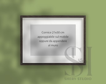 Puede incluir: Un marco de fotos de madera negra con un paspartú blanco y un fondo blanco. El texto en el marco dice "Cornice 21x30 cm appoggiabile sul mobile oppure da appendere al muro".