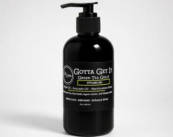 Puede incluir: Un frasco de plástico negro con dispensador de bomba que contiene el gel de peinado Gotta Get It Green Tea Gelly. La etiqueta enumera ingredientes como aceite de argán, aceite de aguacate y raíz de malvavisco, con un volumen de 240 ml.
