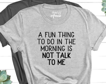May include: Two t-shirts, one gray and one dark gray, with the text "A FUN THING TO DO IN THE MORNING IS NOT TALK TO ME." The shirts have rolled-up sleeves and are knotted at the bottom. The brand logo "PRINT & Arrow" is visible.