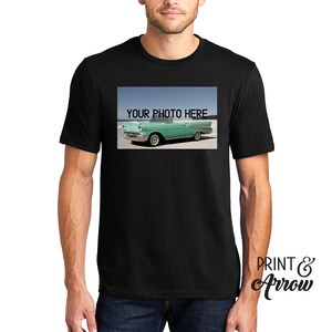 Puede incluir: Una camiseta negra de manga corta con un estampado gr&aacute;fico rectangular en el pecho. El dise&ntilde;o muestra un coche descapotable vintage de color verde claro aparcado en una playa de arena con el texto YOUR PHOTO HERE impreso en negro arriba.