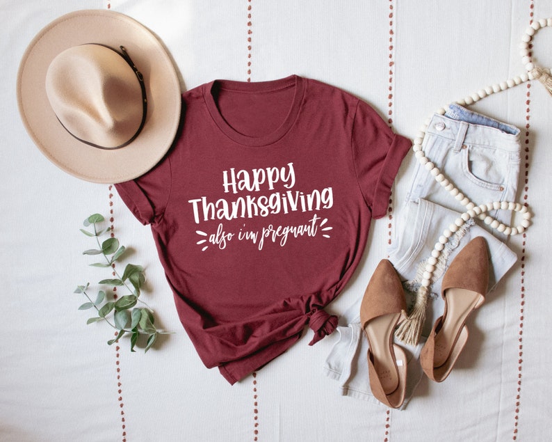 May include: A maroon t-shirt with the text "Happy Thanksgiving also I'm pregnant" in white lettering.
