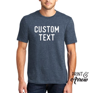 Op de afbeelding: Een blauw heather t-shirt met witte tekst die "CUSTOM TEXT" zegt.