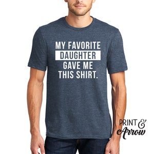 K&ouml;nnte beinhalten: Ein blaues Melange-T-Shirt mit wei&szlig;em Text, der "Meine Lieblings-Tochter hat mir dieses Shirt geschenkt." lautet.
