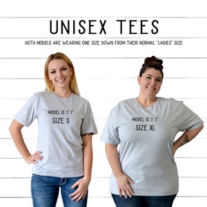 K&ouml;nnte beinhalten: Zwei Models tragen graue Unisex-T-Shirts. Das Model links ist 1,70 m gro&szlig; und tr&auml;gt Gr&ouml;&szlig;e S. Das Model rechts ist 1,57 m gro&szlig; und tr&auml;gt Gr&ouml;&szlig;e XL. Beide Models tragen eine Gr&ouml;&szlig;e kleiner als ihre normale "Damen"-Gr&ouml;&szlig;e.