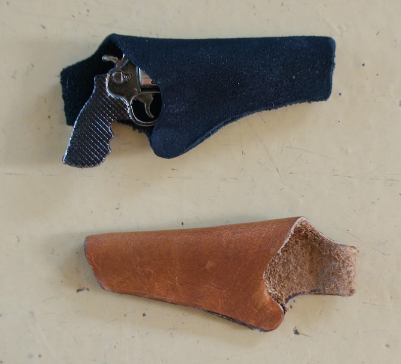 May include: Two leather holsters for a small handgun. One holster is black and the other is brown.