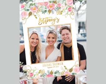 May include: A white photo booth prop with a gold frame and pink floral decorations. The text "Brittany's Bridal Shower September 29th, 2018" is printed on the bottom.