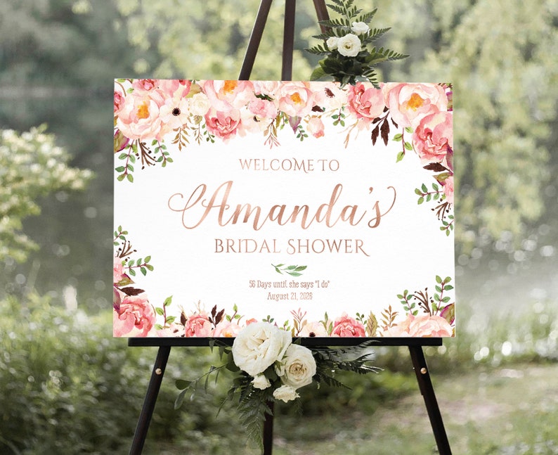 K&ouml;nnte beinhalten: Ein wei&szlig;es Willkommens-Schild mit rosa floralen R&auml;ndern und dem Text "WELCOME TO Amanda's BRIDAL SHOWER 56 Days until she says 'I do' August 21, 2026"