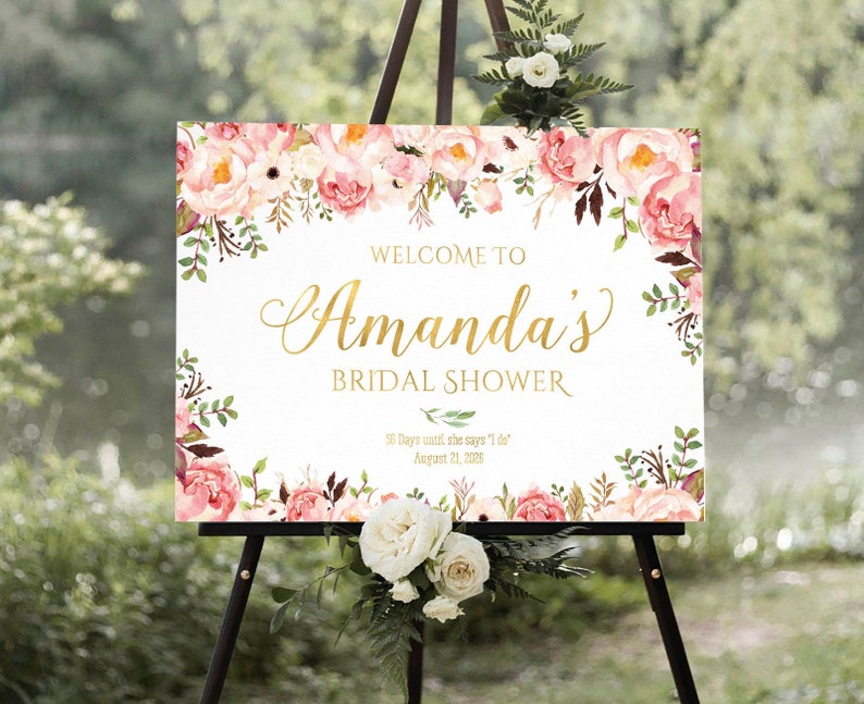 K&ouml;nnte beinhalten: Ein wei&szlig;es Willkommens-Schild mit rosa und gr&uuml;nen floralen R&auml;ndern. Der Text lautet "Willkommen zu Amanda's Bridal Shower" in goldener Schrift. Das Datum ist der 21. August 2018.